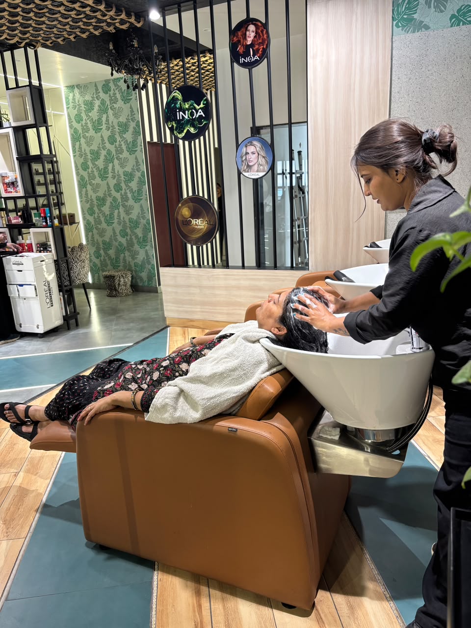 The photo shows a relaxing hair-wash service where the stylist is gently washing